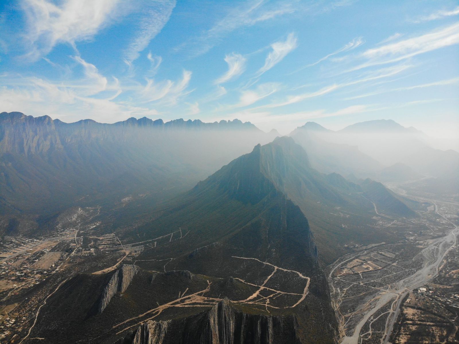 Aerial view of a mountain range and valley under morning mist